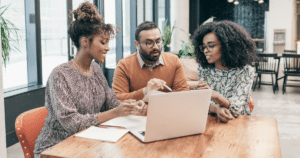 Image of three people sitting around a laptop discussing plans - The Importance of Digital Estate Planning in the Age of Technology